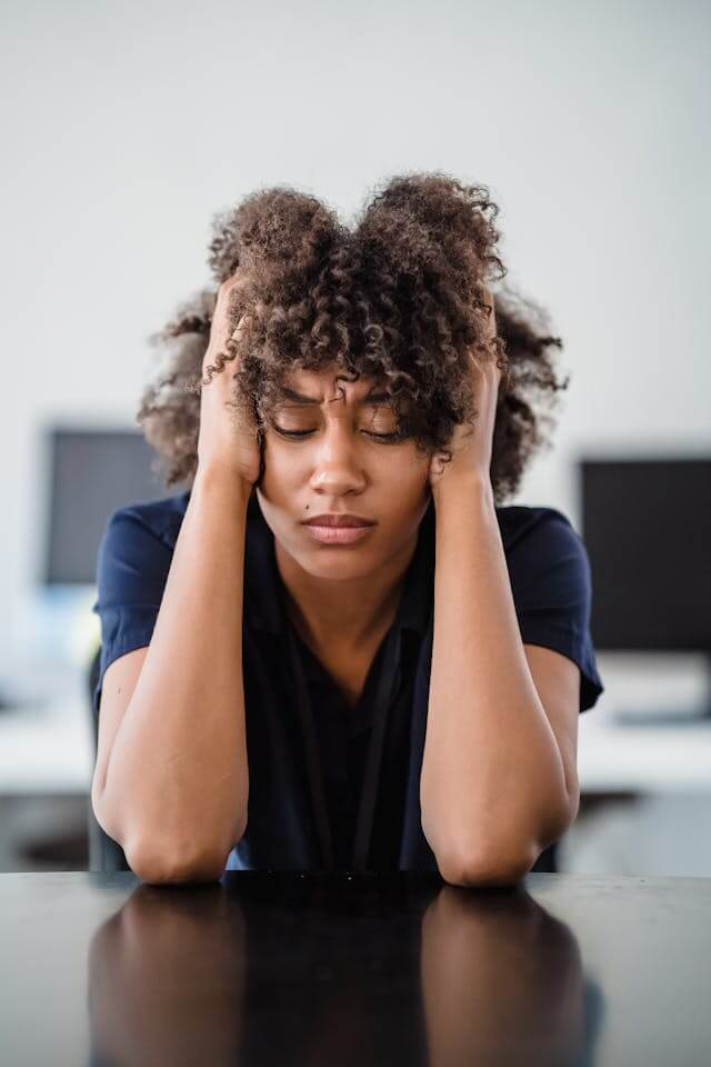 Woman stressed with hands on side of head, eyes closed. Appears with headache pain or mental health decline