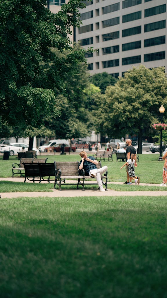 People relaxing and walking in a green urban park surrounded by trees.