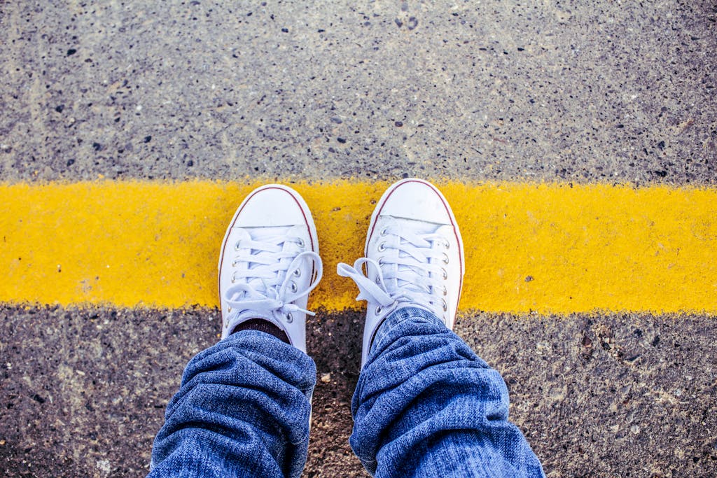 Person standing at a yellow line on pavement, symbolizing boundaries and burnout recovery through protecting personal energy.