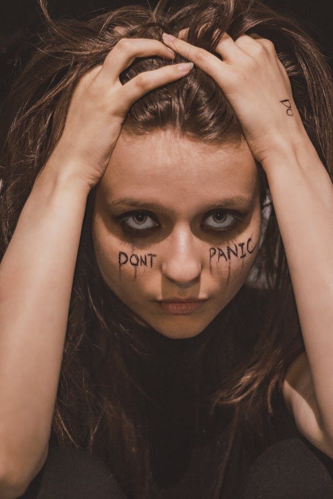 Conceptual portrait of a woman with 'Don't Panic' written on her face, conveying anxiety and physical symptoms.