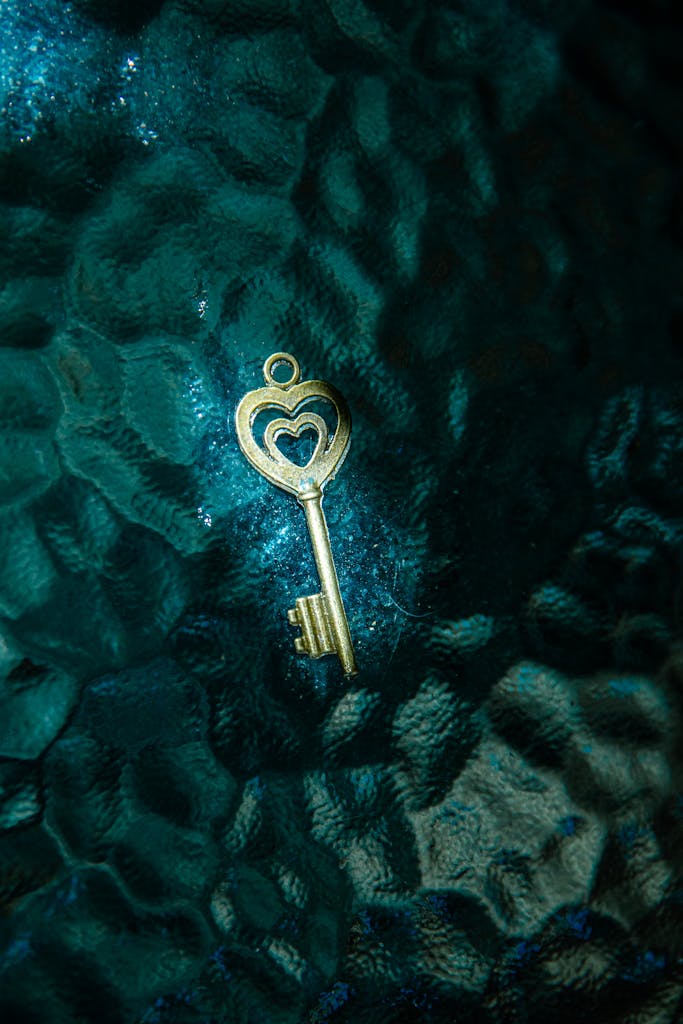 Golden heart key on a teal textured surface, a visual metaphor for unlocking vagus nerve health and resilience.
