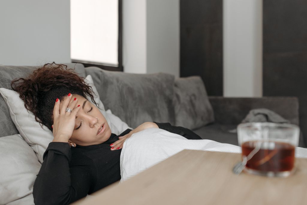 Woman lying on a couch appearing tired all the time possibly ill.